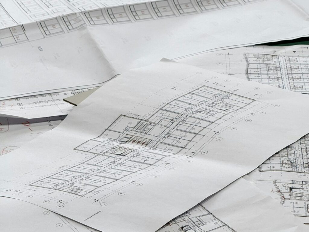 Architectural plans and site drawings spread across a work surface